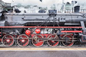 Retro steam train stands on the station before departure at spring evening time.