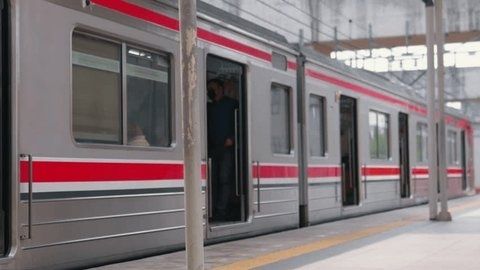 Modernt rödvitt pendeltåg vid en stationsplattform